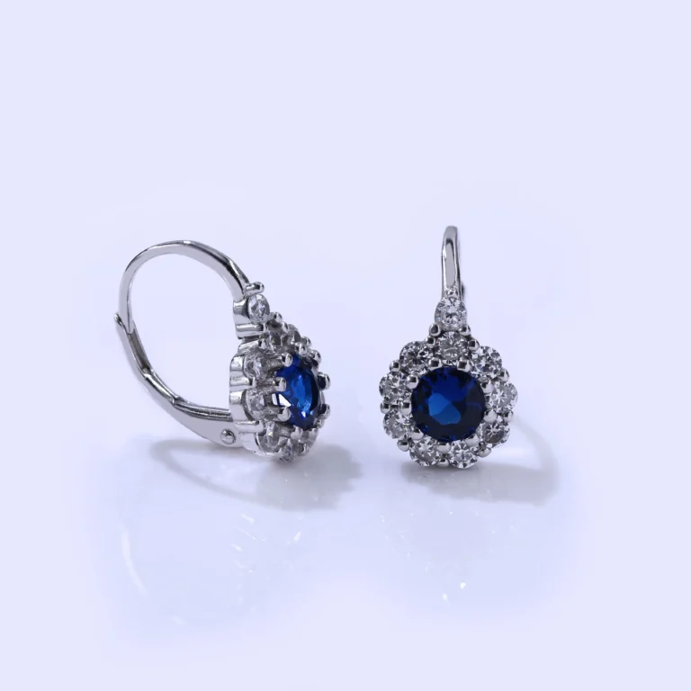עגילים צמודים מכסף עם אבן כחולה ומסביבם קישוטי אבנים, מושלמים לסיטונאות תכשיטים.